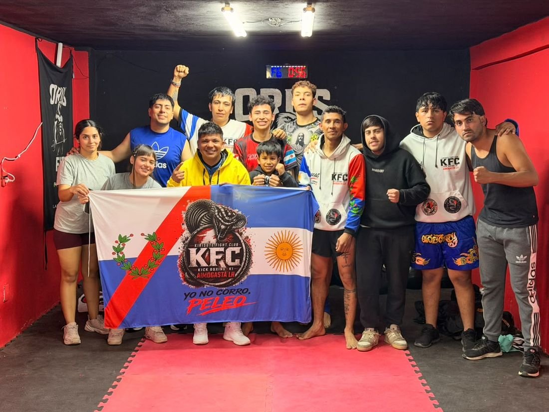 Socios y equipo de competencia de ORUS posando con la bandera del equipo en la sala roja del gimnasio